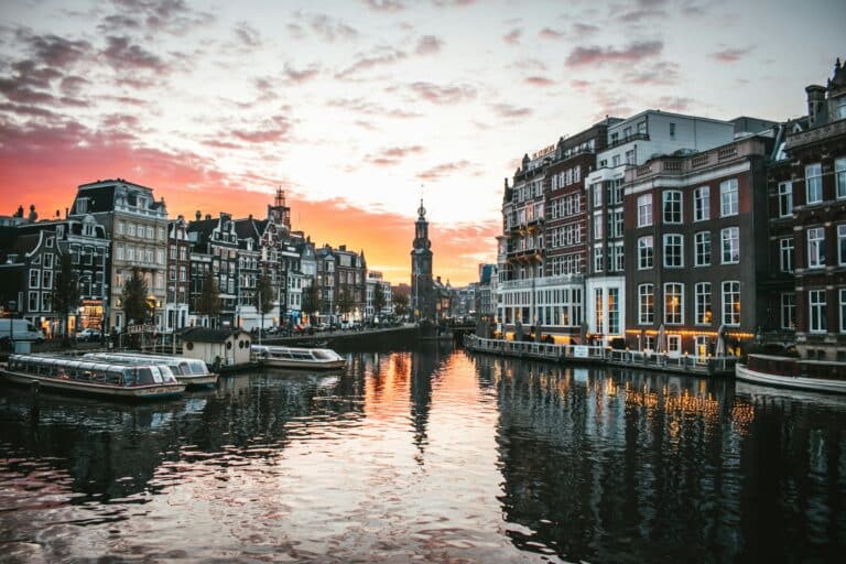 Sunset reflecting on the canal at Muntplein with historic buildings in Amsterdam