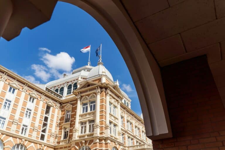Historic building with a Dutch flag viewed through an archway in The Hague