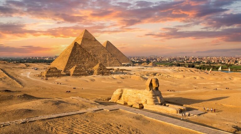 An aerial view of the Great Sphinx and the Pyramids of Giza in Egypt during a colorful sunset.