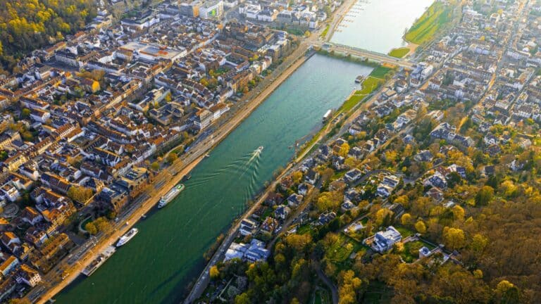 An aerial view of the city of Bonn, Germany, with the Rhine River flowing through the center during a golden sunset.