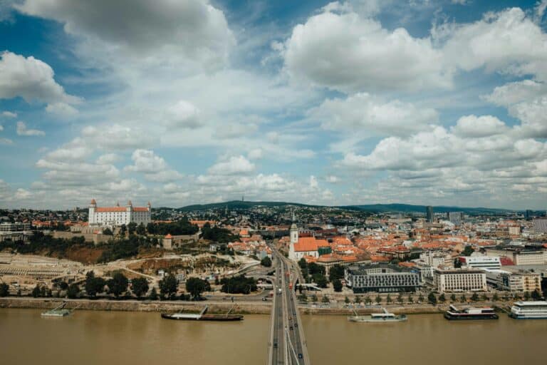 Aerial view of Bratislava, Slovakia, showing the historic Bratislava Castle on a hill overlooking the Danube River.