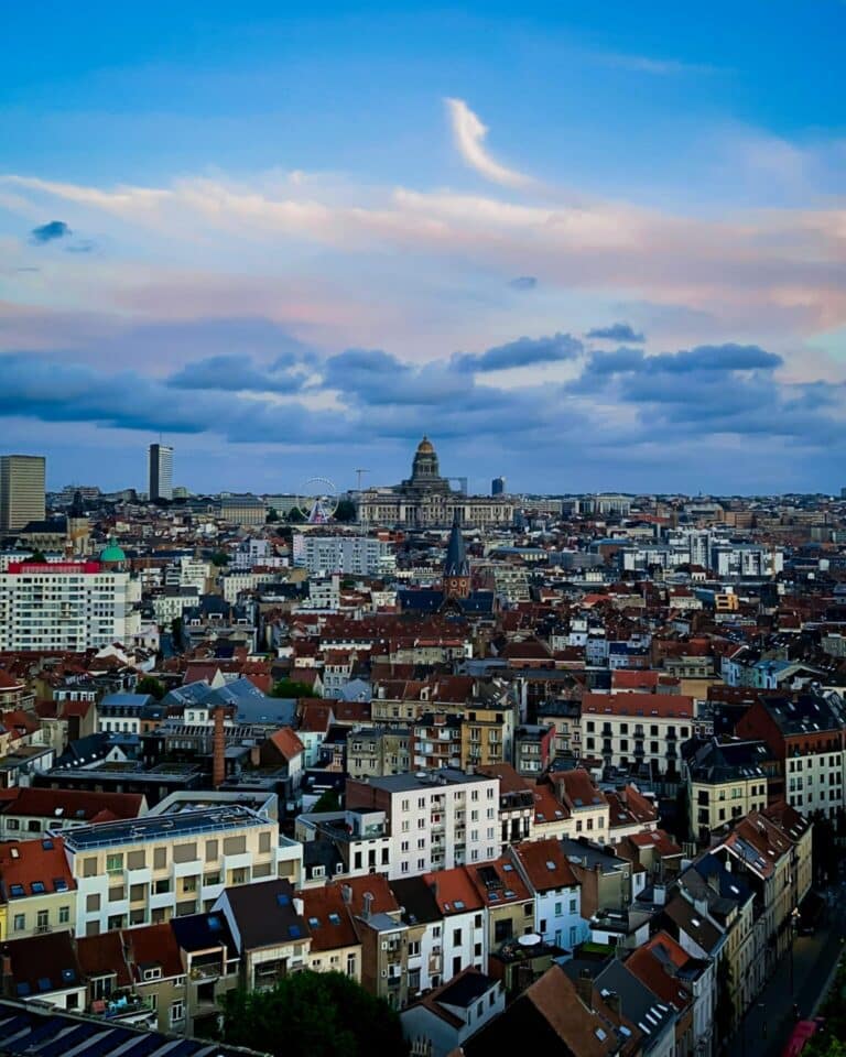 An elevated view over the rooftops of Brussels, Belgium at dusk, with the Palace of Justice on the horizon.