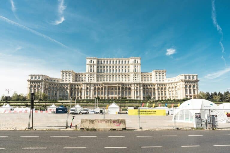 The grand Palace of the Parliament in Bucharest on a sunny day with event tents set up in the foreground.