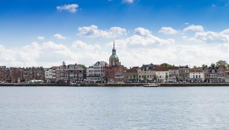 A scenic view of the Dordrecht waterfront in The Netherlands, featuring the historic Groothoofdspoort city gate.