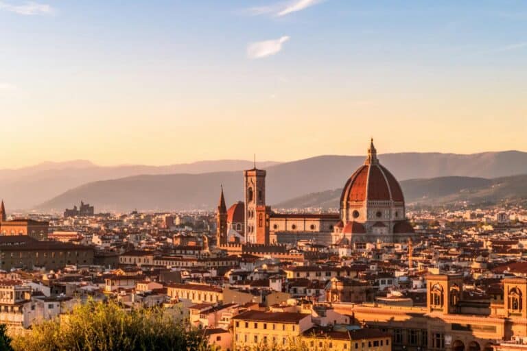 A panoramic view of the Florence skyline at sunset, with the iconic Florence Cathedral in the center.