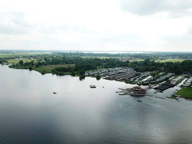 An aerial view of the village of Giethoorn in the Netherlands, with houses and marinas bordering a large lake.
