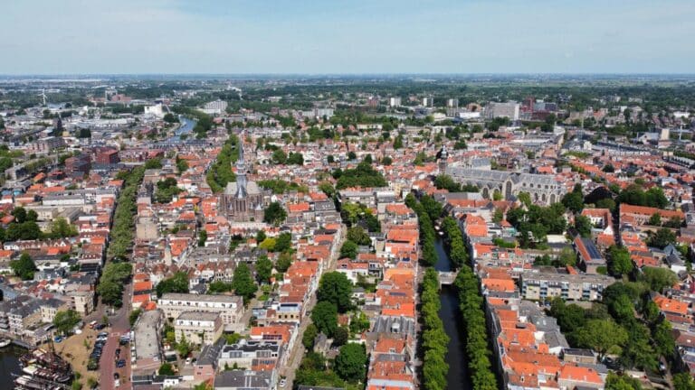 An aerial panorama of the historic city center of Gouda, featuring the Sint-Janskerk and Gouwekerk churches.