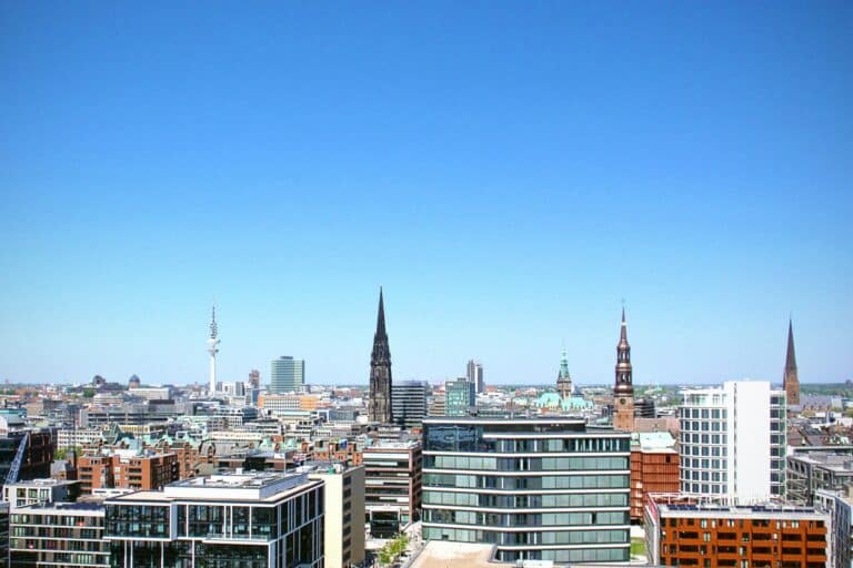 Elevated view of the Hamburg city skyline on a sunny day, with the historic spires of multiple churches.