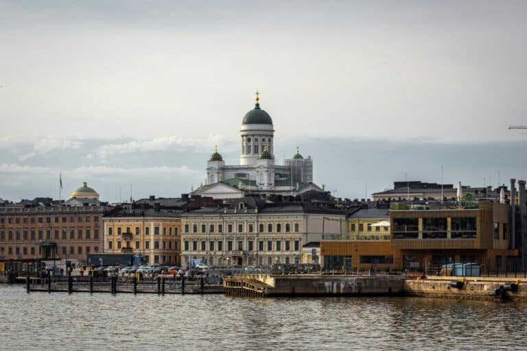 The Helsinki Cathedral and surrounding city buildings are seen from across the water on a cloudy day.