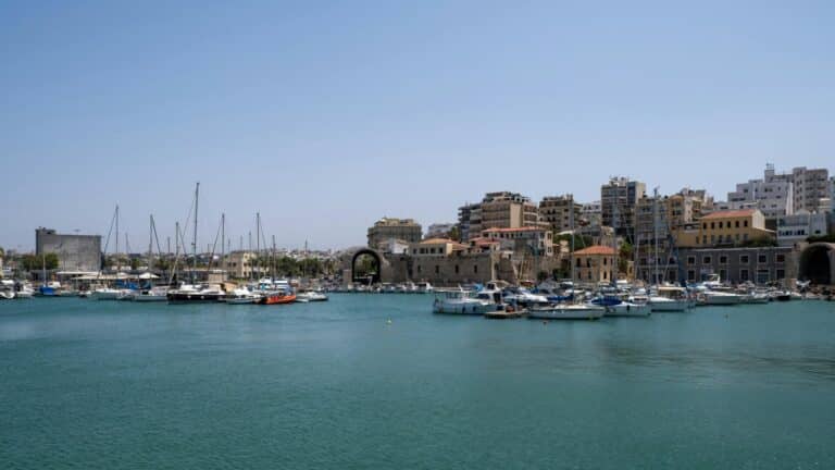 View across the teal water of the Old Venetian Harbor in Heraklion, with many boats moored.