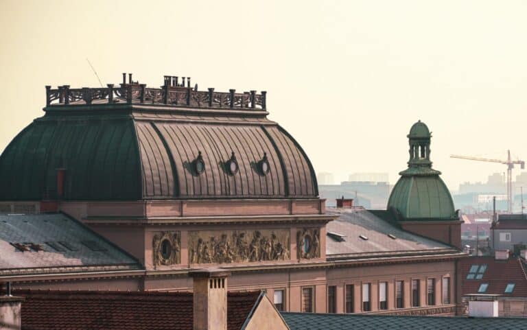The ornate domed rooftop of the Juliusz Słowacki Theatre against the hazy skyline of Kraków, Poland.