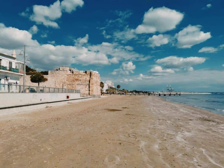 The medieval Larnaca Castle on the edge of a wide sandy beach under a beautiful blue sky in Cyprus.