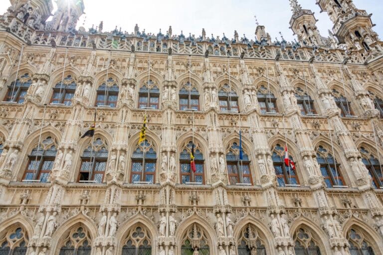 A low-angle view of the highly ornate and detailed Gothic facade of the Leuven Town Hall in Belgium.
