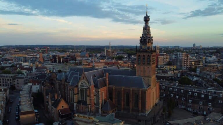 An aerial view of the Stevenskerk and the surrounding city of Nijmegen at dusk under a cloudy sky.