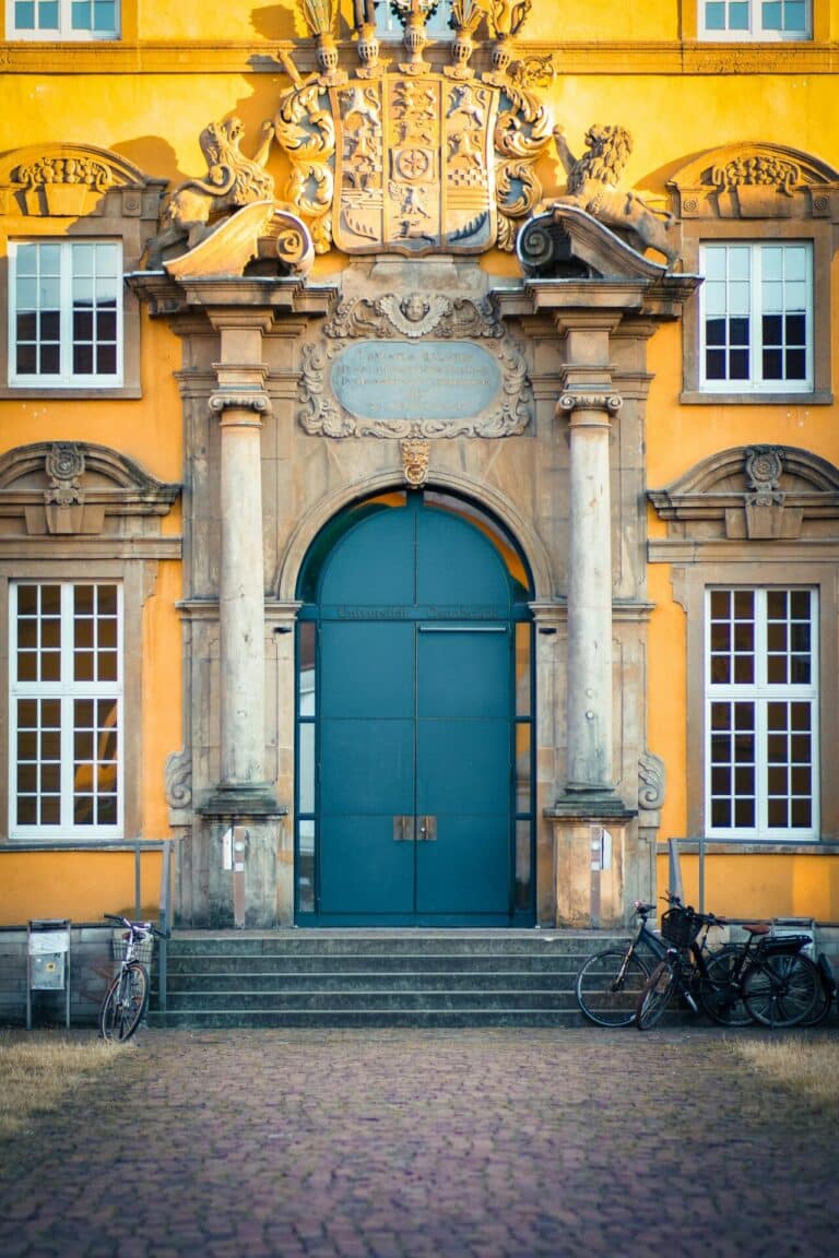 The ornate yellow baroque facade of the University of Osnabrück, housed in the historic Osnabrück Palace.