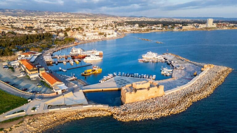 An aerial view of the Paphos harbour and the historic Paphos Castle on the coast of Cyprus at sunset.