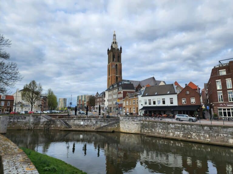 A scenic view of the Roerkade in Roermond with the historic St. Christopher's Cathedral tower against a cloudy sky.