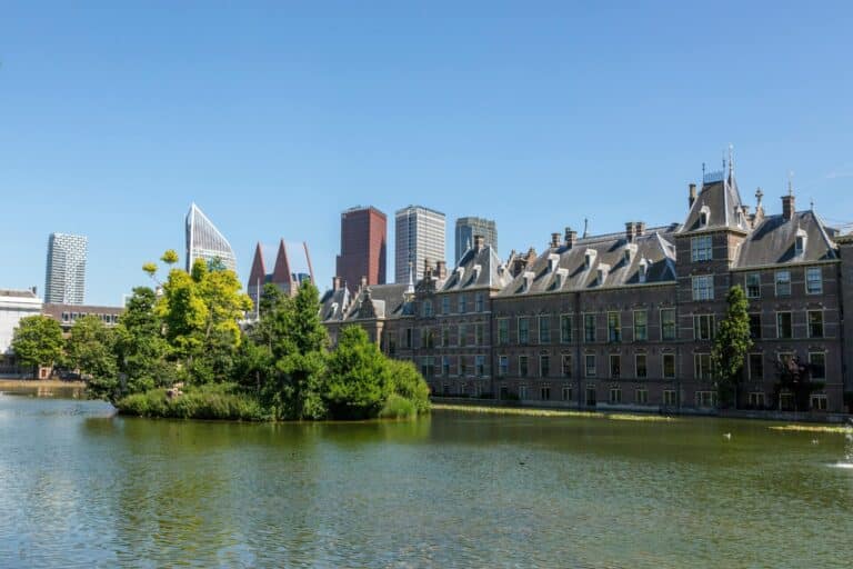 The historic Binnenhof complex and the modern skyline of The Hague seen from across the Hofvijver pond.