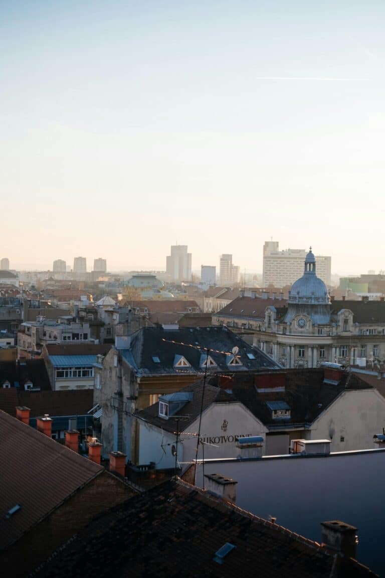 A high-angle view over the historic rooftops of Zagreb, with the modern city skyline in the background.