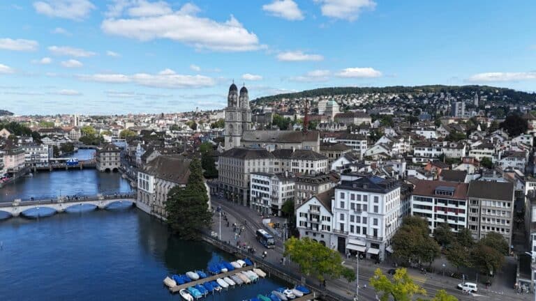 An aerial view of Zurich's old town, featuring the iconic Grossmünster church and the Limmat river.