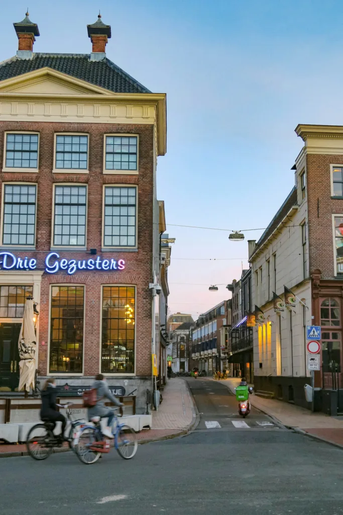 City Game  Groningen two cyclist cycling with the most famous pub in Groningen in the background