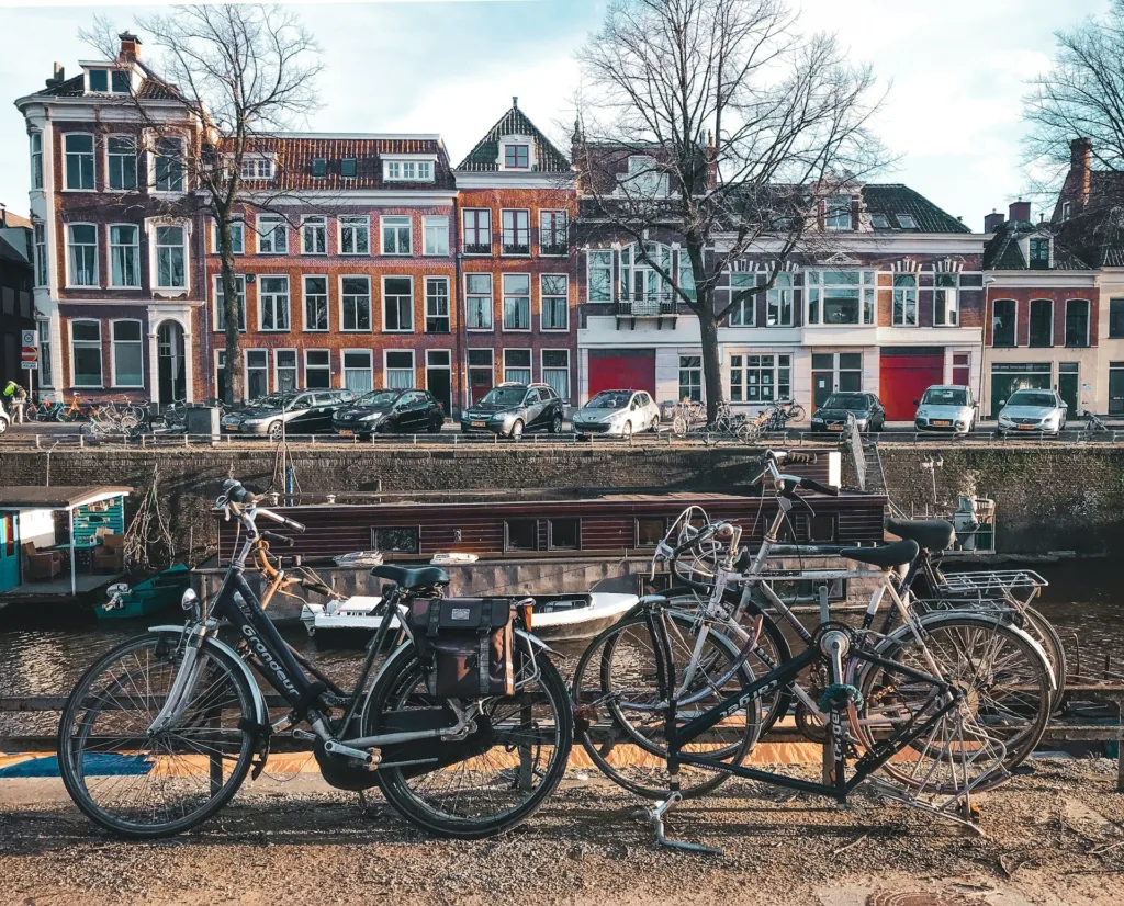 City Game  Groningen bicycles parked along a scenic canal in Groningen, showcasing the city's charming architecture and cycling culture.